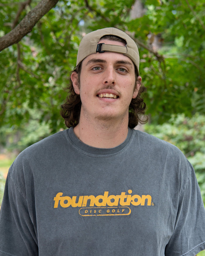Silas wearing a gray t-shirt with 'foundation' logo outdoors