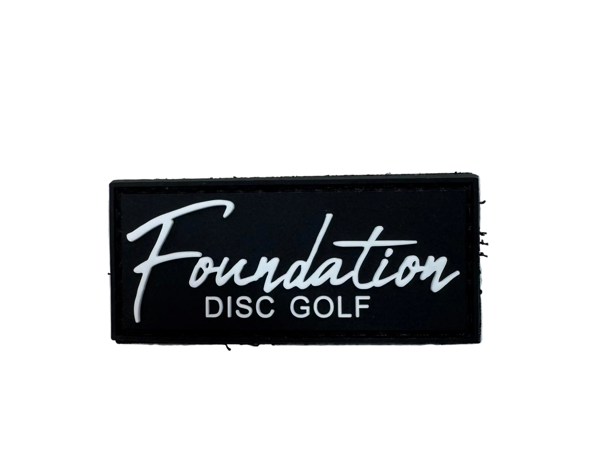 Black patch with 'Foundation Disc Golf' text on a textured surface